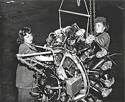 Two Marine Corps women repairing an airplane engine