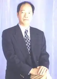 A middle aged Chinese man in a dark blue suit, white shirt, and blue and white patterned tie
