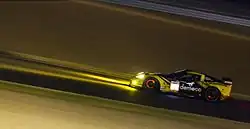 A yellow and black grand touring car in night time conditions
