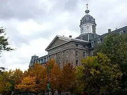 A photo taken in 2019 of the building that used to be the Montreal Institute for the Deaf and Mute partially obstructed by trees as seen from rue Saint-Denis.