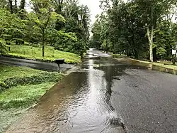 A flooded road in New Jersey with mostly low-lying areas of the road flooding.