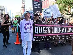 An original member of the Gay Liberation Front stands beside the 2019 Queer Liberation March banner