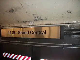Metal sign on tunnel wall with 42 St–Grand Central name