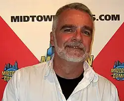 Smiling, gray-bearded man in white shirt