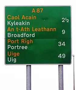 A Scottish sign using the typeface on the Isle of Skye, with place names given in both Scots Gaelic and English, and distances shown in miles.