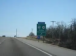 A green sign reads "ALT US 75, SH 16, Beggs, Muskogee" with an arrow. A blue plaque above it reads "CAMPING".