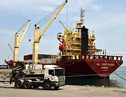 Red and yellow cargo ship being unloaded by cranes
