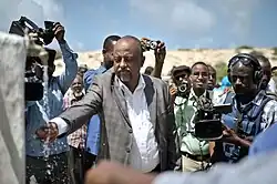 Official tastes the water of a new well in front of journalists in Mogadishu, Somalia, 2014.