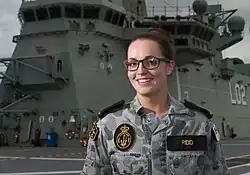 A woman wearing a camouflaged military uniform on the deck of a ship