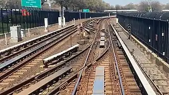 A section of the line that runs along the Van Wyck Expressway. There are two tracks connected by switches. The expressway is to the left, behind a fence.