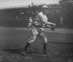 A black-and-white image of a man in a white old-style baseball uniform