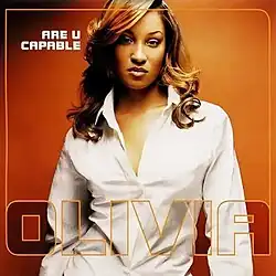 A woman wearing a white button front shirt standing in front of an orange background.