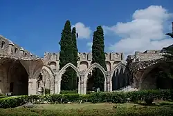 Ruined walls and arches in a courtyard with cypres