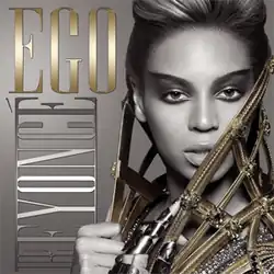 The front face of Beyoncé, in grayscale. She is wearing heavy make-up and has her hair folded back. A metallic cape is wound around her neck, which she holds at her front. Her right hand is empty, but on her left hand she wears a metallic glove. On the right of the image, the words "Ego" and "Beyoncé" are written in capital fonts. The word Ego and Knowles' cape is colored gold.