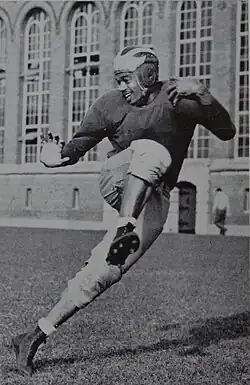 Mann in his football gear posing as if he is running