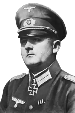 A man wearing a peaked cap and military uniform with an Iron Cross displayed at the front of his uniform collar.