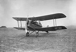 Three-quarter view of military biplane on landing ground