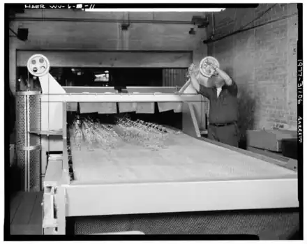 conveyer with glass on it and a man inspecting it