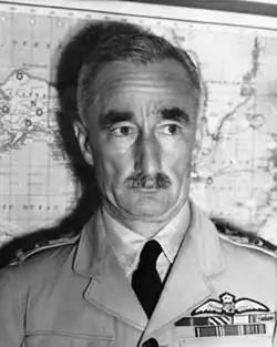 Head-and-shoulders portrait of moustachioed man in light-coloured military uniform with pilot's wings on left pocket