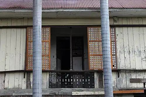 An opened grilled ventanilla below a capiz shell window of the convent of Saints Peter and Paul Parish Church in Calasiao, Pangasinan.