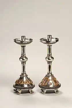 Pair of silver candlesticks, ornately decorated with heart shapes and scroll patterns.