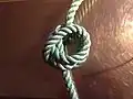 Step 4 of tying Cross constrictor knot: the far side loop folded over the simple knot