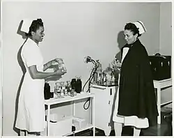 Caption on back: "Captain Mary L. Petty, of Chicago, left, who headed the first contingent of Negro Army nurses to arrive in the European war theater, is shown here while on duty as Chief Nurse at Ft. Huachuca, before her assignment overseas. Assisting her in inspecting an operating room at the camp hospital is 2nd Lt. Olive Bishop, of New York. Both nurses were recruited for Army duty by the American Red Cross, official nurse recruiting agency for the Army."
