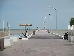 An image of a boardwalk over a body of water. A sign says "Chicxulub Puerto Mexico"
