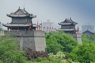 City walls with two prominent towers, partially obscured by trees