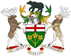 A central shield with the upper part showing the red cross of St. George and the lower part showing three golden maple leaves on a green background. There is a black bear on top of a knight's helmet above the shield with a moose to the left and a Canadian deer to the right. The province's motto "Ut incepit Fidelis sic permanet", Latin for "Loyal she began, loyal she remains" is written below the crest.