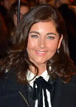Woman with shoulder-length brown hair wearing a white shirt and dark jacket