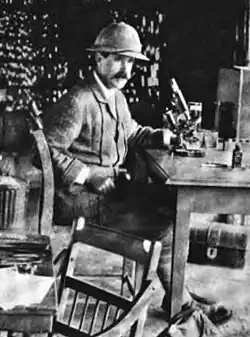 Cristy in Uganda, sitting at a desk with a microscope