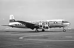 A black-and-white photograph of a four-engine aircraft at an airport