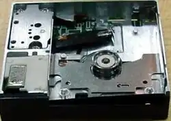 DataPlay optical drive engine internals viewed from above a unit produced without any top cover; above the circular piece is the laser pickup. The laser pickup is built on a piece of silicon.[18]