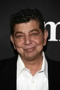 caucasian male in his fifties wearing an open-neck white shirt and suit jacket