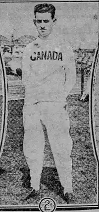 Black and white photo of a young adult male dressed in white pants and white shirt with Canada written across the chest