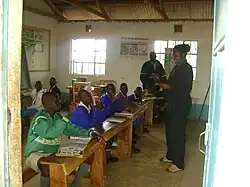 Smiling teacher standing in front of eight older boys in Africa