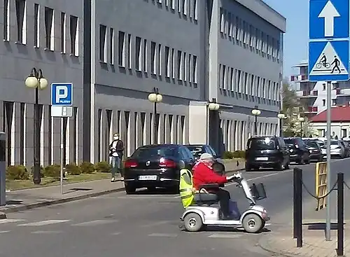 Disabled woman riding a bicycle path in an electric wheelchair, Tomaszów Mazowiecki, Saint Anthony Street, 2020