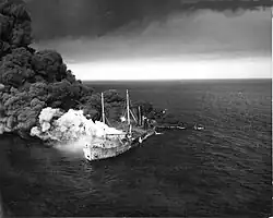 Smoke and fire pour from Dixie Arrow's starboard side as she sinks