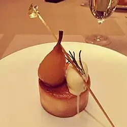 A dessert made of ingredients place on a brown pastry base on a white plate.