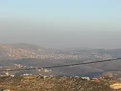 In the front, beneath the telephone cable, is mount 725, an illegal Israeli outpost of Yitzhar. Beneath it, crossed by the telephone cable, is Einabus. Covering most of the farther area is the municipality of Qabalan. Behind the right side of Qabalan is Talfit, and behind it is Qaryut. Behind the middle of Qabalan is Ahijah.