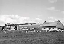 A black-and-white photo of a farm in a valley