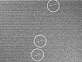A noisy image showing a few bright dots marked by circles