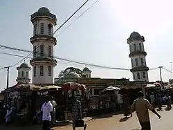 A mosque with beige walls and four spires topped with green domes