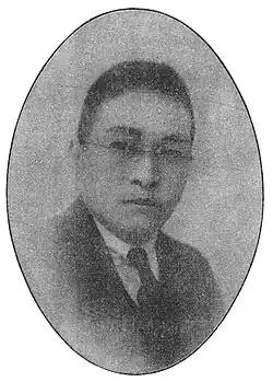 A black-and-white portrait of a man in a suit; he is wearing glasses.