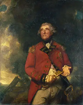 An portly English officer with a ruddy complexion and black eyebrows, stands in military dress against a background of smoke from a cannon. He holds a very large key in one hand and gestures with the other.