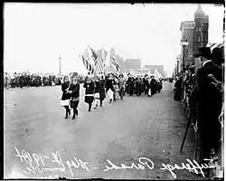 Black-and-white photo of people marching down a city street.