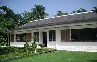 A white-washed bungalow with a lawn in front