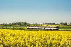 An EN57 passes through fields around the village