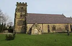 Stone church with tall tower in grassed churchyard